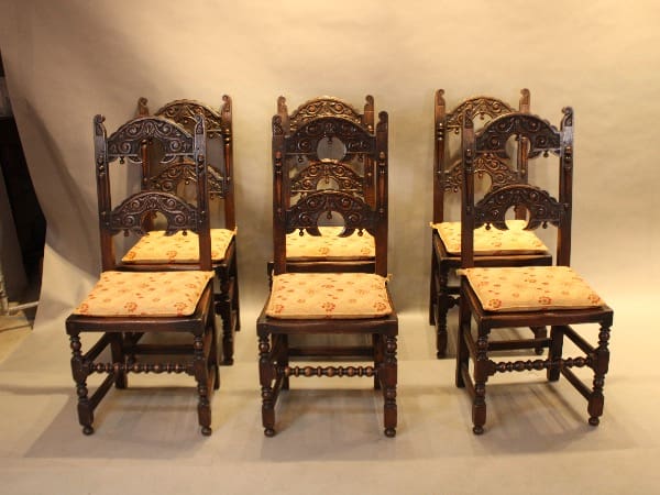 Six ornate wooden chairs with floral cushions.