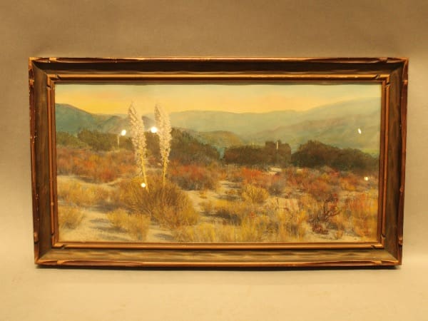 Framed desert landscape painting with mountains.