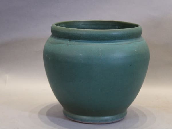 Green ceramic pot on a gray background.