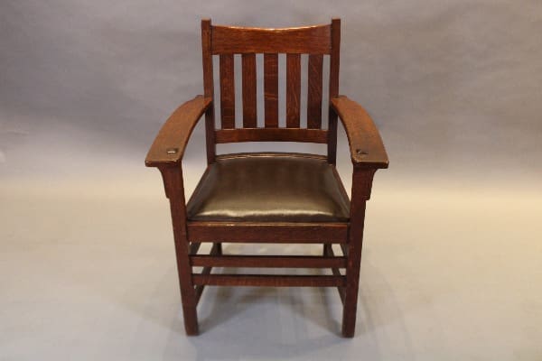 Wooden chair with slatted backrest and arms.