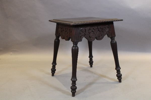 Intricately carved antique wooden table with legs.