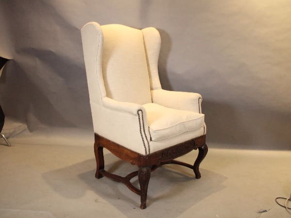 White wingback armchair with wooden legs.