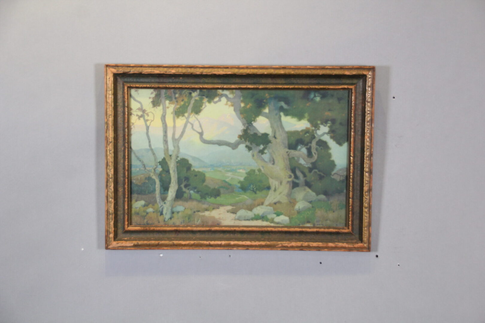Framed landscape painting with trees and path.