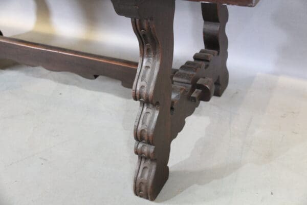 Ornate wooden table leg on light floor.