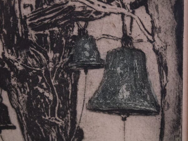 Two bells hanging from tree branches.