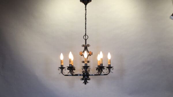 Wrought iron chandelier with lit candles.