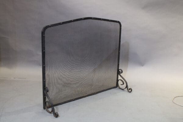 Black metal fireplace screen with decorative scrolls.