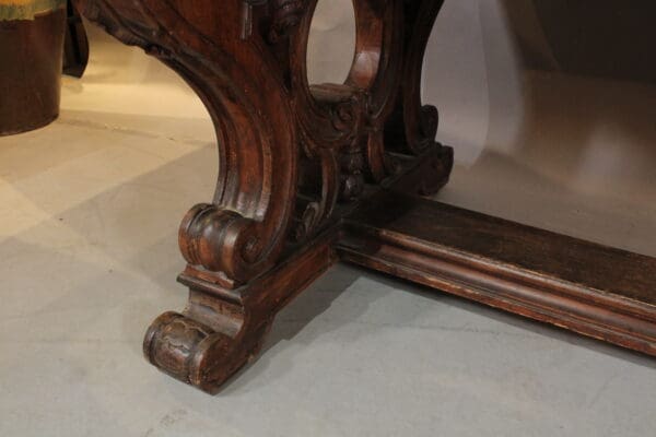 Ornate wooden table leg on grey floor.