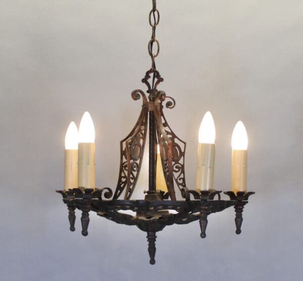 Vintage wrought iron chandelier with glowing bulbs.