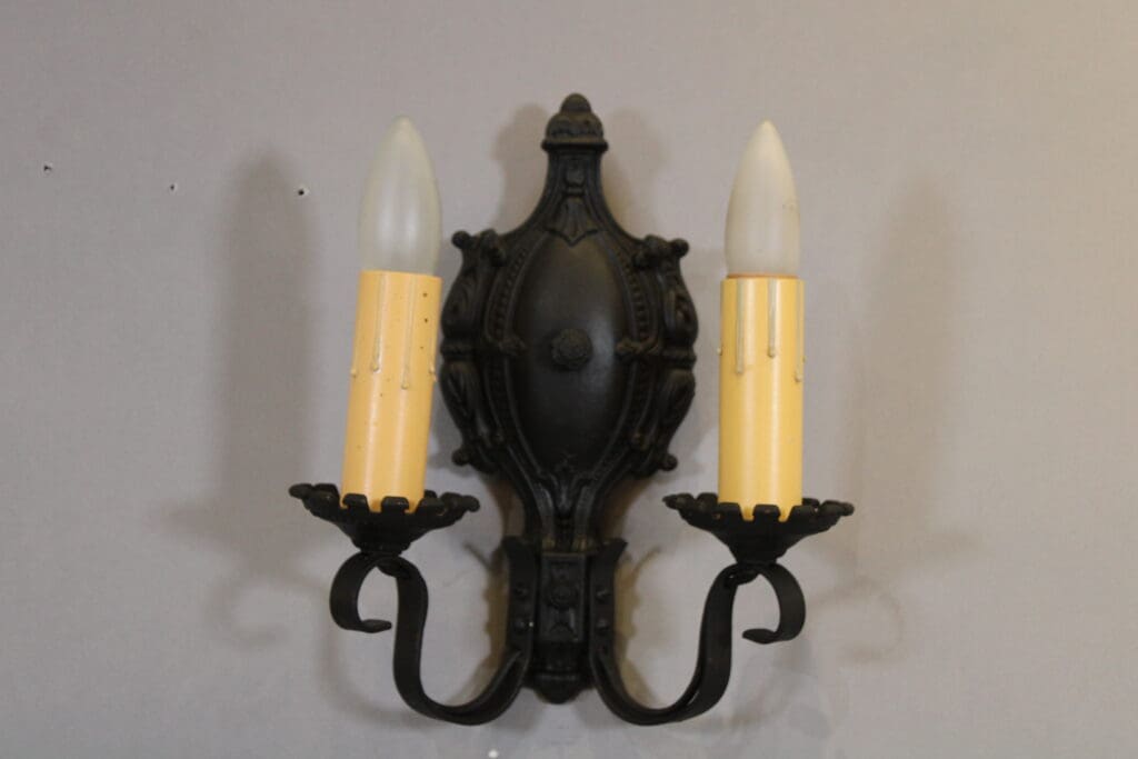 Ornate black wall sconce with two bulbs.