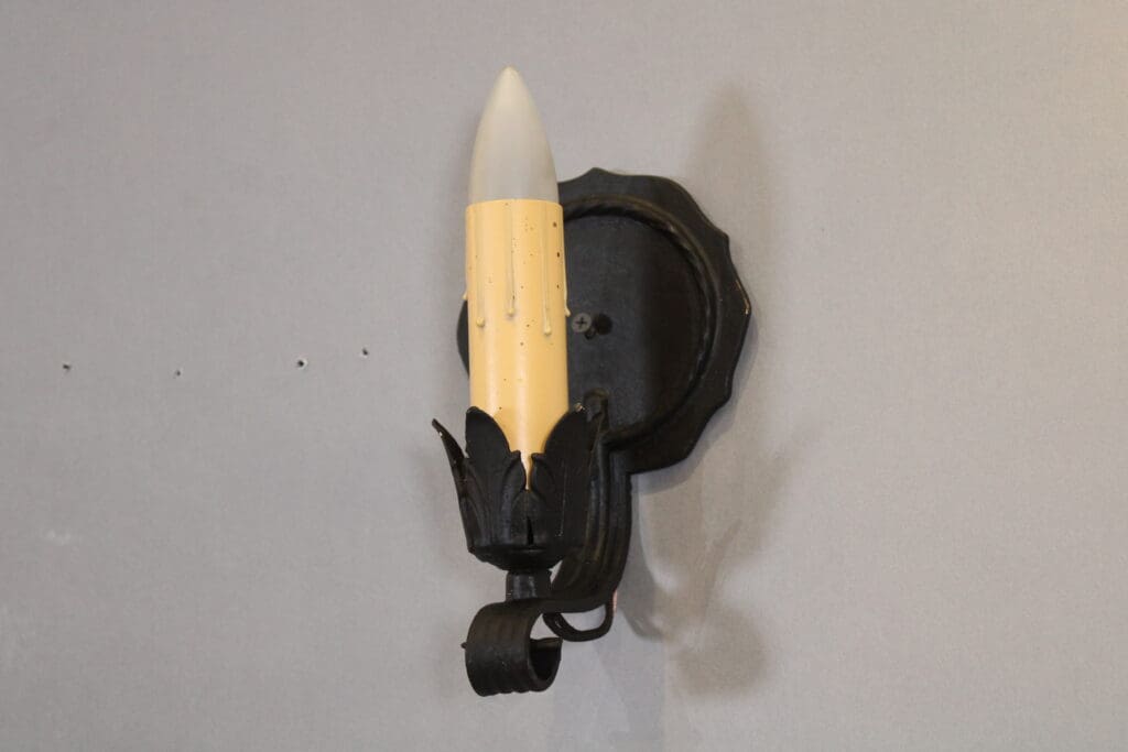 Wall-mounted decorative candle-shaped light fixture.
