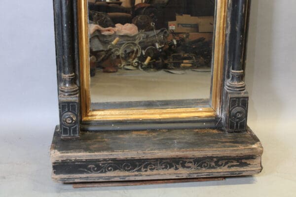 Antique mirror with ornate black wooden frame.