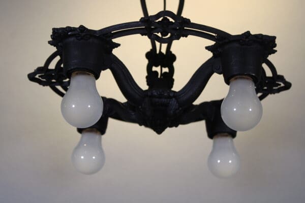 Vintage chandelier with four white light bulbs.