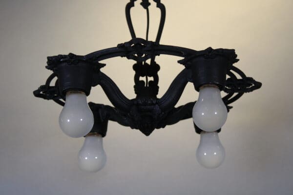 Black chandelier with four hanging light bulbs.