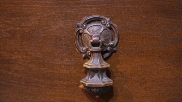 Ornate metal door knocker on wooden surface.