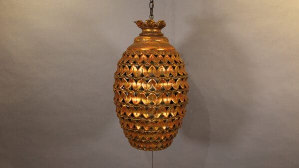 Ornate golden hanging lantern against plain background.