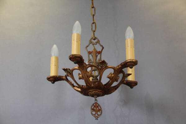 Ornate chandelier with four candle-shaped bulbs.