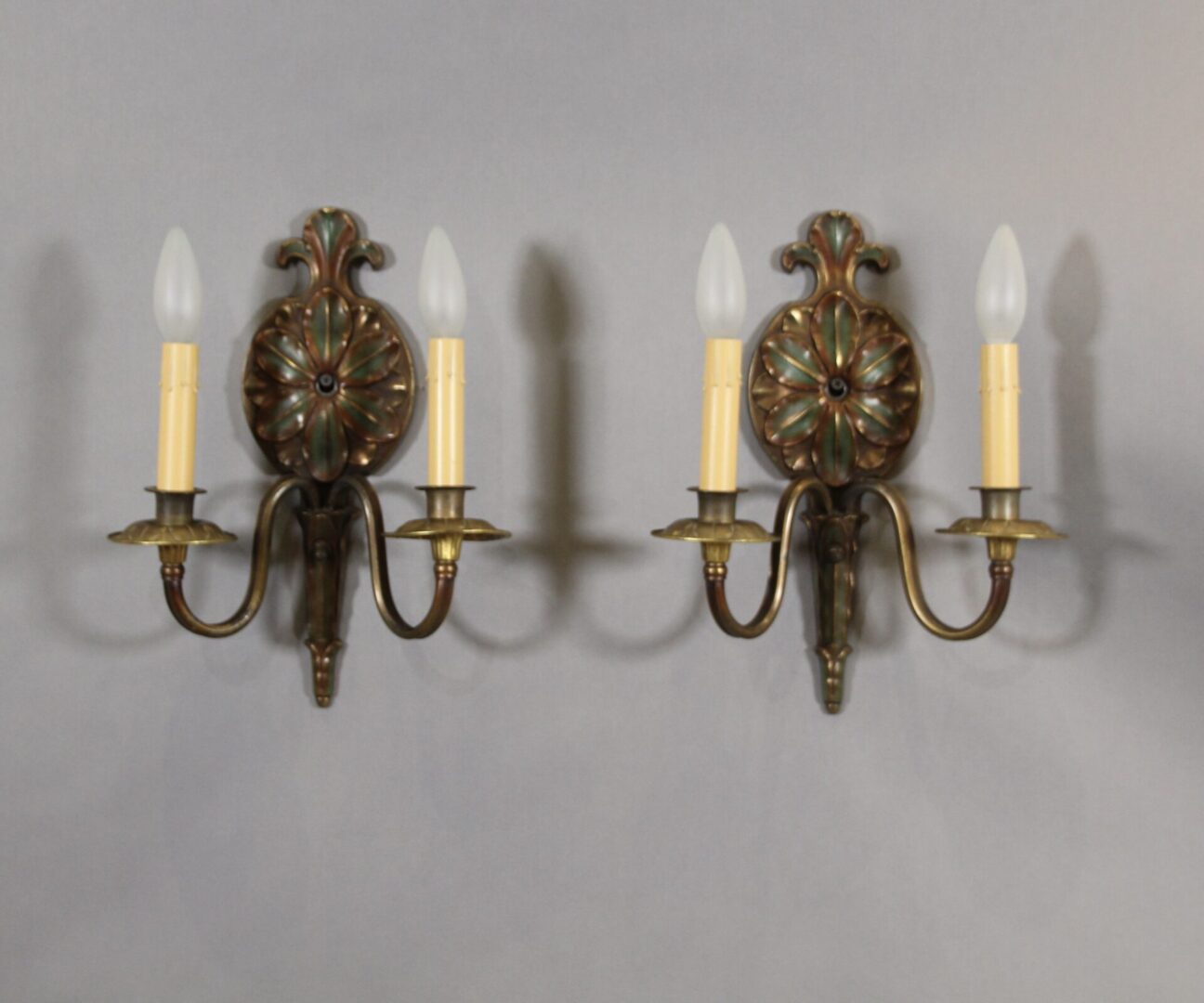 Vintage dual-arm wall sconces with candles.