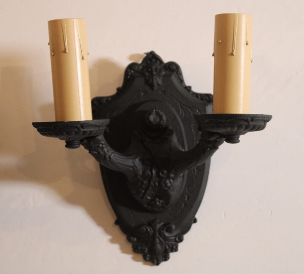Ornate black wall sconce with two candles