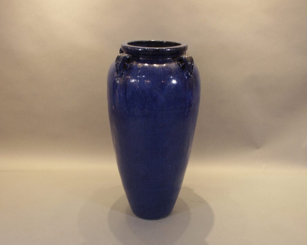 Tall glossy blue ceramic vase on beige background