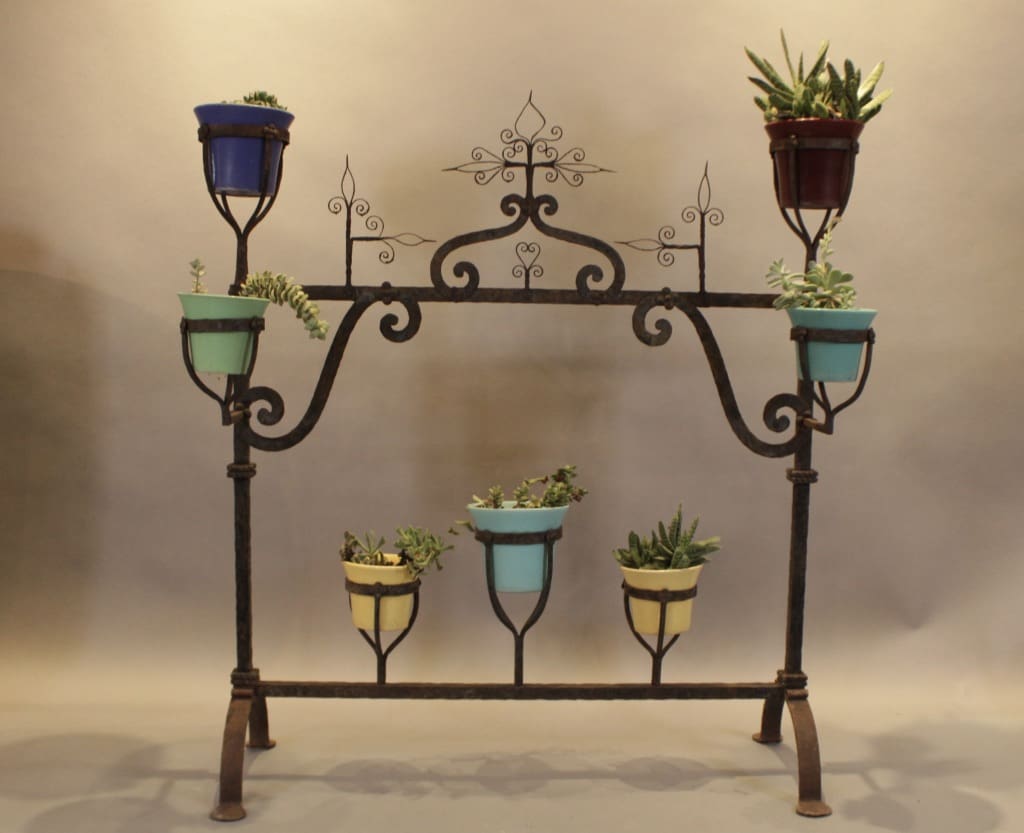 Wrought iron plant stand with colorful potted succulents